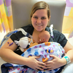 Mother holding twin preemie babies on her chest.