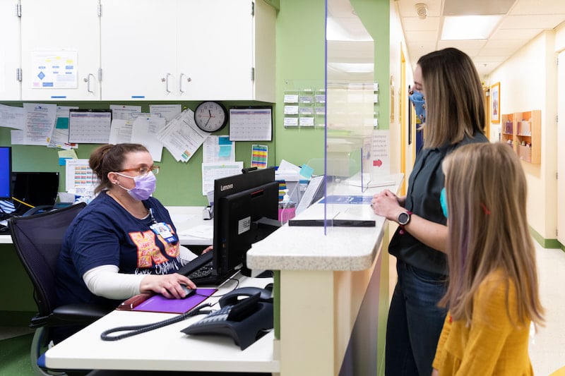 A family talks with a clinician who is using a computer at the Children's Mercy Genetics Clinic.