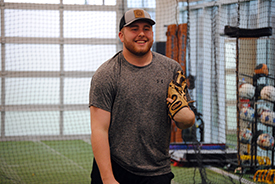 Bradley “Gage” Gulley smiling while holding a baseball glove in one hand at Village West.