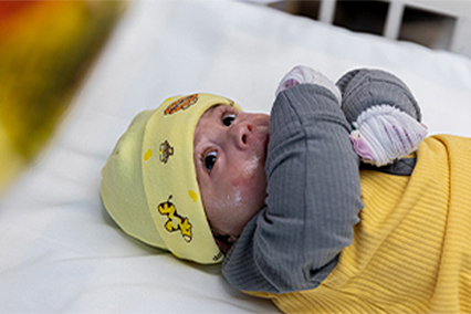 Baby Jaciel Ceballas Lemus laying in crib with hands wrapped in bandages.