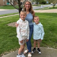 A mom and two young boys pose together outdoors.