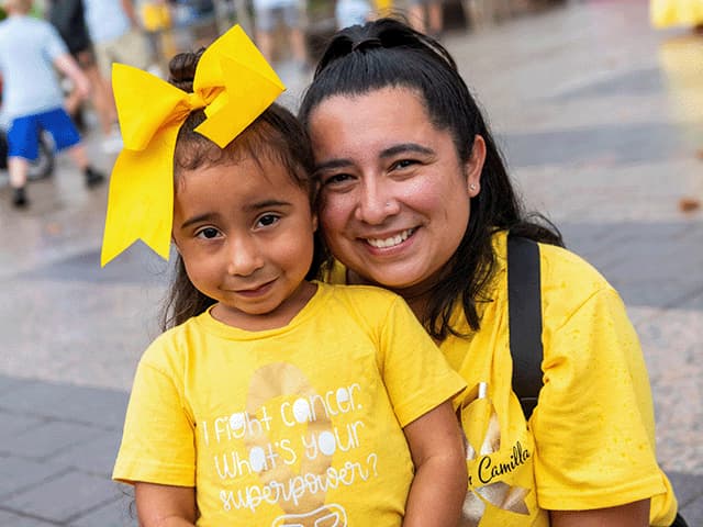 Mother and daughter smiling together in matching yellow shirts. 