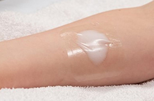 A patient's arm with white numbing cream on it covered by a clear bandage.