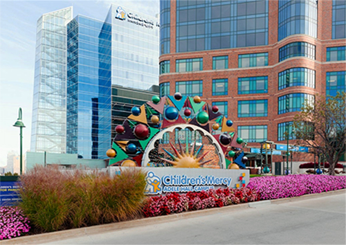 Photo of the Children's Mercy Adele Hall Campus sign with the Children's Mercy Research Institute building in the background.