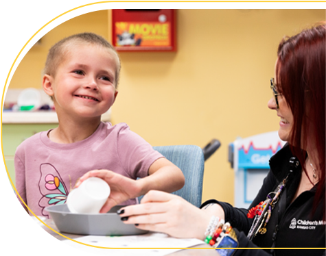 Children's Mercy patient, Parker, smiling while doing an activity with a Children's Mercy staff member..