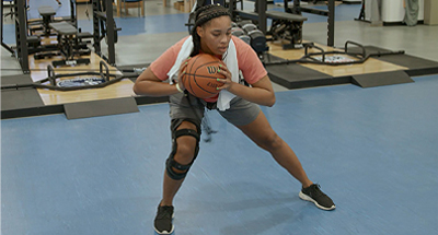 Physical therapy patient doing lateral stretch with basketball in her hands