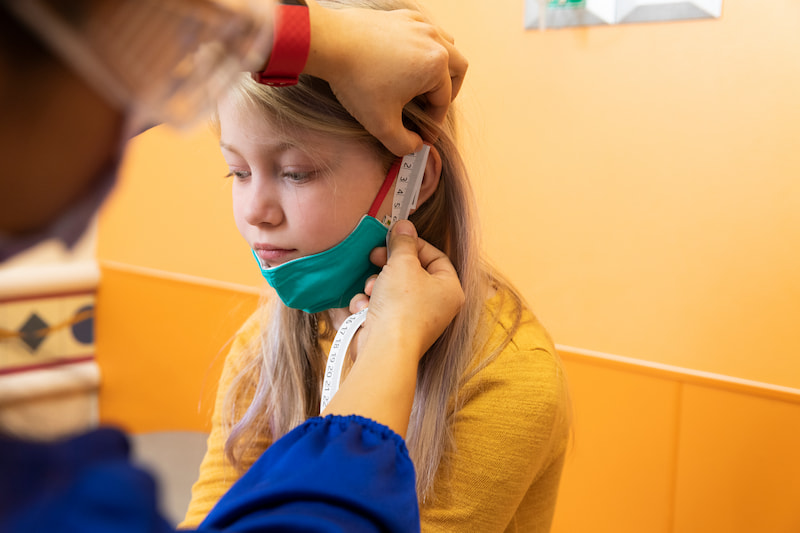 A clinician measures the side of a female patient's face at the Children's Mercy Genetics Clinic.