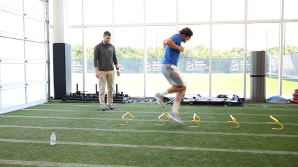 A young adult man exercises at the Children's Mercy Sports Medicine Center while a trainer looks on.