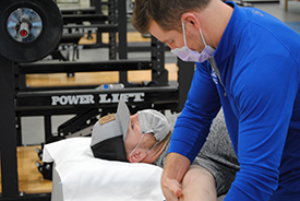 Gage Gulley having his shoulder stretched by physical therapist, Michael Denning.