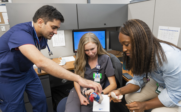 Three Children's Mercy fellows look at a model heart together.