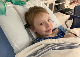 Austin Hasenohr resting and smiling in a hospital bed.