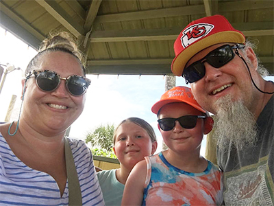 Emily Barker shown here with her family: husband, Brian; daughter, McKinzie; and son, Hudson. All are smiling.