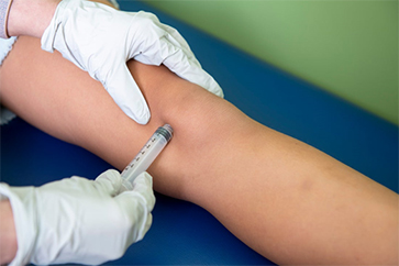 Knee joint being injected with a needle.