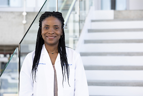 Marianne, Children's Mercy Research Associate Masters, standing in the CMRI building. She is wearing a white lab coat and smiling.