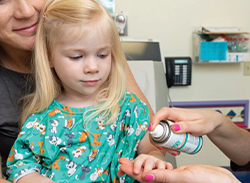 Cold spray being applied to a child's hand.