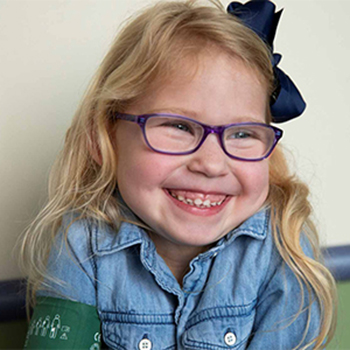 Little girl wearing eyeglasses and a big smile.