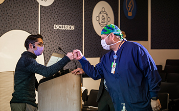 Surgery fellow fist bumping a Children's Mercy surgeon in the Children's Mercy auditorium.