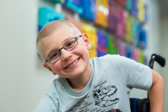 patient alex on campus hallway smiling with glasses on – in wheel chair 