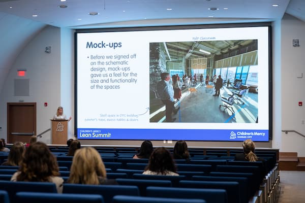 Woman with blond hair presenting PowerPoint slide of "Mock-Ups" from Lean summit 2025 conference