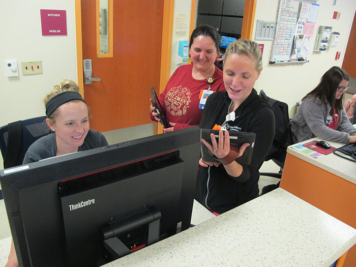 Three Children's Mercy providers looking at computers and smiling.
