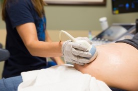 Closeup of echocardiogram being performed on a pregnant belly