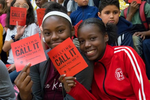 Two school girls holding Red Card anti-bullying cards 