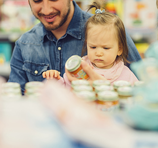 Family with young baby holding baby food jar in a grocery store.