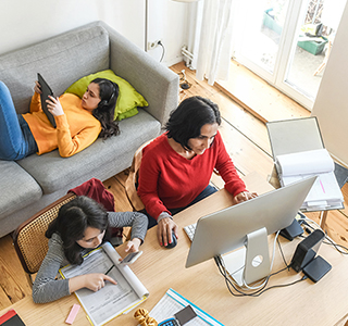 mom working at home and two children doing schoolwork next to her