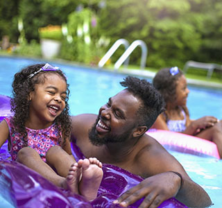 Happy family swimming together in a pool 