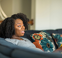 Mom sits on couch and listens to toddler talking to her. 