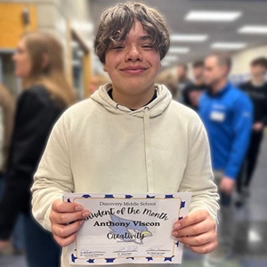 Anthony wearing white hoodie, holding "Student of The Month" Certificate.