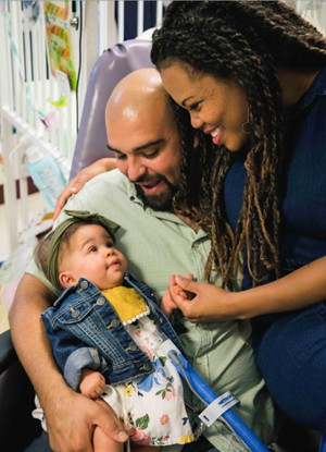 Patient, Birdie as a baby pictured with mom and dad in patient room