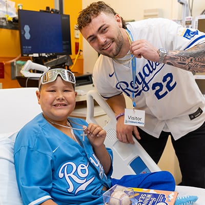 Jaxson and Kansas City Royals player Carter Jensen display matching necklaces while visiting in a hospital room at Children's Mercy. 