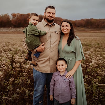 Family of four standing together in a field outdoors