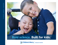 Two young brothers pose next to each other. One is in a wheelchair.