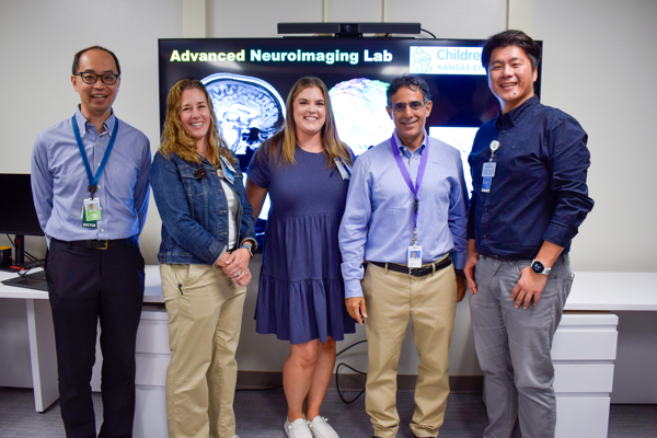 Advanced Neuroimagine Lab research team stands in front of screen at ribbon cutting celebration.