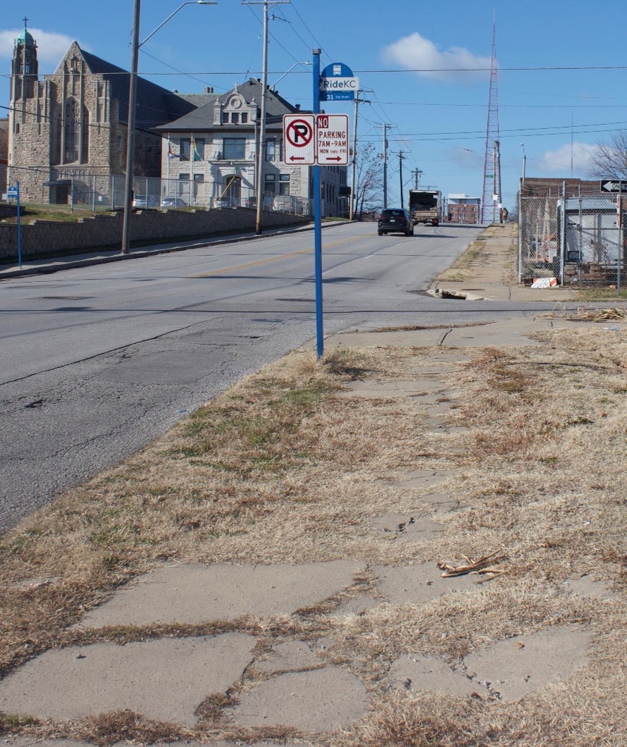 Example of a bus stop highlighted by community members based on concerns over safety and accessibility. The grass grows over the sidewalk, which is not level.