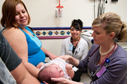 Two doctors with the Culture and Language Coaching Program providing care for a baby with its mother