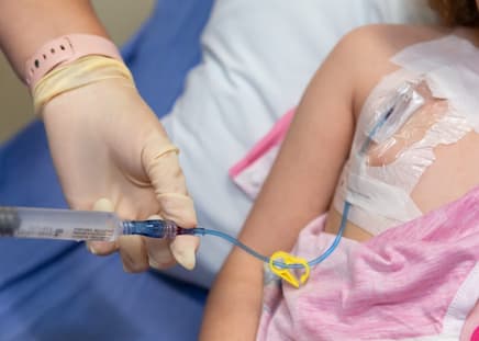 nurse using syringe to put water into port.
